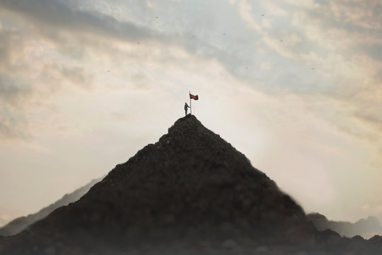 woman plants his flag on the mountain peak as a sign of success