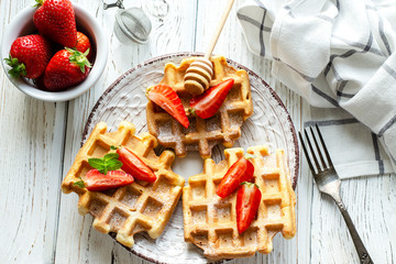 Fresh strawberries and Belgian waffles on wooden background