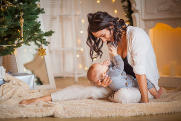 mother with her newborn son near the Christmas tree