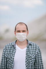 Man in a protective, medical white mask, looking directly at the camera.