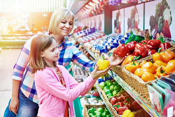 Mother and daughter chooses bell peppers in store