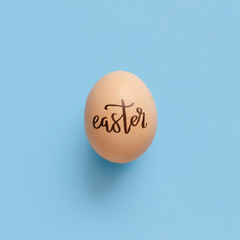 Egg with inscription EASTER over light blue background