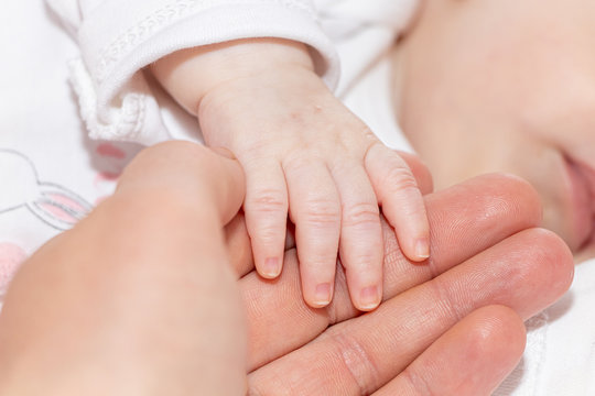 Newborn baby holding mother's hand, close up and main focus on newborn baby hand