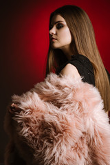 Fashion portrait of woman wearing a fur on black and red background