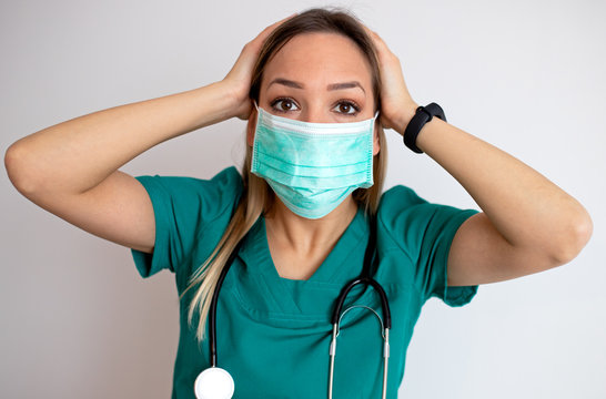 Young nurse feeling extremely shocked and surprised, anxious and panicking, with a stressed and horrified look against white wall – stock image