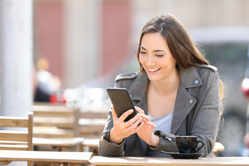 Happy woman checking phone in a coffee shop