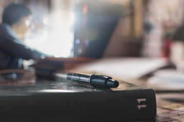 textbook with pen on desk on background boy with computer, online education