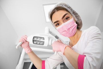 Fototapeta na wymiar The patient's first-person view at the examination by the dentist lies in the dental chair. Doctor Dental surgeon examines an oral cavity with the help of somatological tools