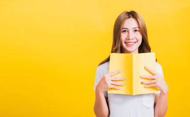 woman stands holding yellow book or diary