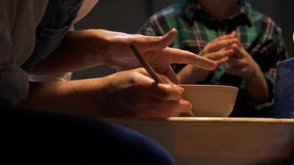 Woman sculpts a plate on a pottery wheel
