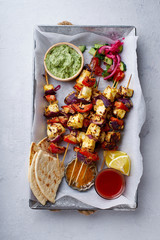 Paneer tikka starter kebabs with mint chutney and chapati. Traditional indian cuisine, grilled cheese skewers with onion and bell pepper slices. Vegetarian dish marinated in tikka sauce.