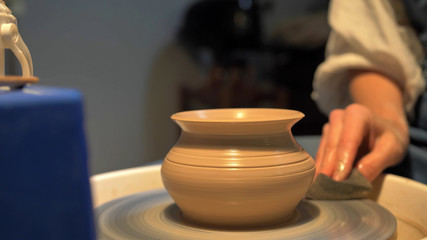 Woman makes a pot on a pottery wheel in a workshop, slow motion