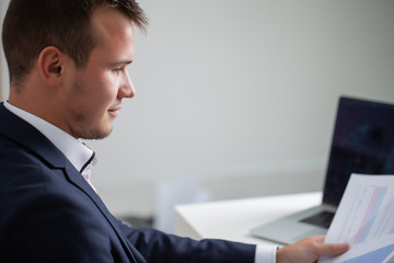 Solid businessman in a jacket works with documents in the office of the company