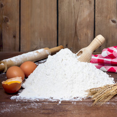 flour, spoon, eggs  and roller on wooden background