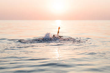 Young woman swimming in the sea in sunset
