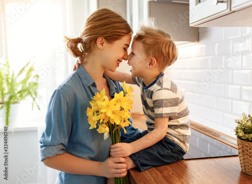 Little son congratulating mother in kitchen.