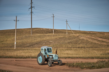 Old blue tractor amid small mountains and wires