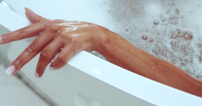 Closeup woman hand on the edge of bathtub with foam - video in slow motion
