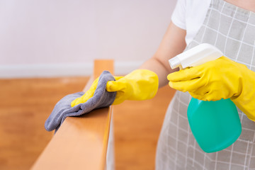 Maid cleaning stairway rail by using alcohol and liquid cleaning solution. Covid-19 protecting concept, alway cleaning equipments in daily life. Sanitation and healthcare.