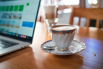 Hot aroma cappuccino coffee cup on wooden table work from home with laptop