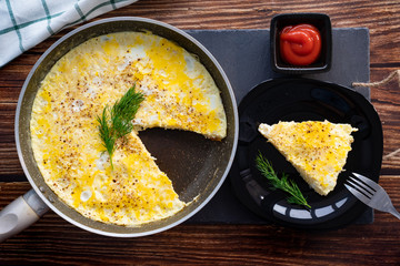 omelet with herbs ketchup frying pan and on plate.