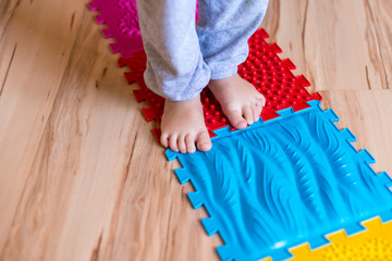 Orthopedic foot mat for child gymnastic. Small children with a flat-bottomed stomach goes barefoot on an orthopedic foot mat for the appointment of an orthopedist.