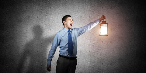 Horrified businessman holding glowing lantern