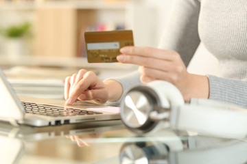 Girl paying music with credit card on laptop