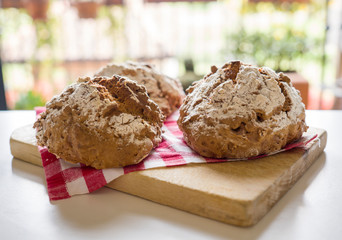 Homemade bread on cutting board with red and white checkered napkin.