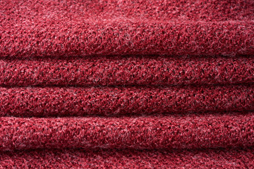 Closeup red texture of woolen knitted fabric. Pattern of several layers of red fabric.