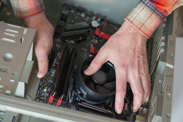 Installing a new motherboard in the system unit. Computer repair and upgrade. Close-up of the hands of a master repairing a computer. selective focus