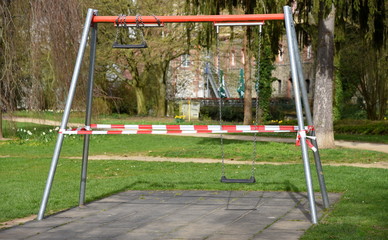 Wegen Covid 19 abgesperrte Schaukel auf einem Kinderspielplatz