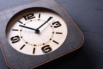 Wooden clock made in hand on wooden background. Close-up. Place for text.