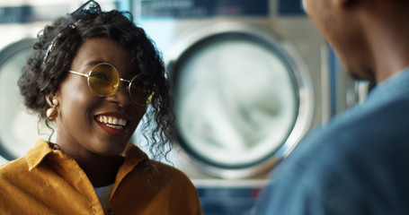 Rear of African American young guy meeting girl and hugging at laundry service room. Close up of...