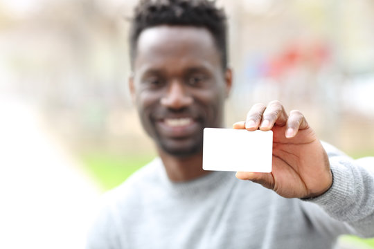 Happy black man showing blank credit card in the park