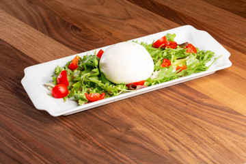 close up of burrata with salad on a wooden background
