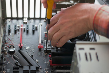 Installing a new motherboard in the system unit. Computer repair and upgrade. Close-up of the hands of a master repairing a computer. selective focus