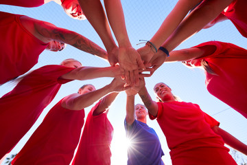 Low Angle View Of Manager Joining Hands With Womens Soccer Team During Pep Talk Before Match 