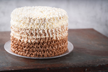 Elegant celebration cake on vintage table behind light wall background, selective focus. Copy space. Celebration concept. Trendy vintage Cake.
