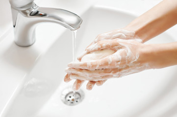 Hand Washing in white sink. Water flows from a faucet at soapy female hands. Covid-19 coronavirus...