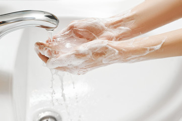 Hand Washing in white sink. Water flows from a faucet at soapy female hands. Covid-19 coronavirus protective measure. - obrazy, fototapety, plakaty