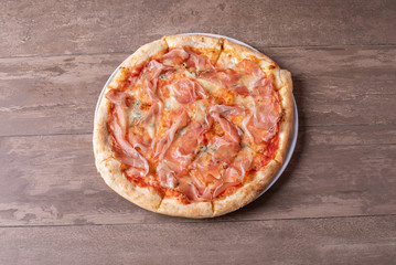 details of fresh baked pizza with ham on a wooden table