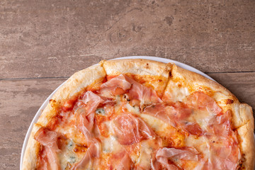 details of fresh baked pizza with ham on a wooden table
