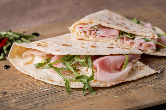 details of tasty italian piadina with ham and arugula