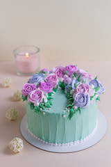  Tasty cake with cream roses for wedding, birthday. Beautiful, fashionable cake. Turquoise on a pink background with a candle