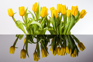 Żółte tulipany i lustrzane odbicie w kałuży.  Rozlana woda i odbicie kwiatów.