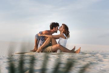 selective focus of passionate young couple kissing on blanket on beach