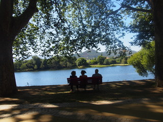 Three people sitting on a bench by the river among beautiful greenery, Camino de Santiago, Way of St. James, Journey from Barcelos to Ponte de Lima, Portuguese way, Portugal
