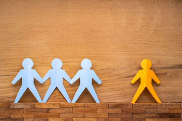 Paper cutout human figures separate by wide space between them on wood background