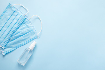 Mask and spray alcohol for doctor. Protection covid-19 virus concept on blue pastel background. Flat lay, top view, copy space.